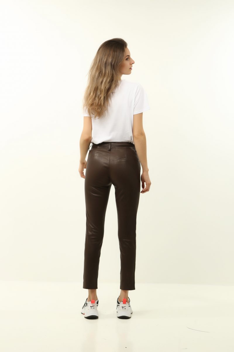 blonde woman wearing black leather pants with a white top back view