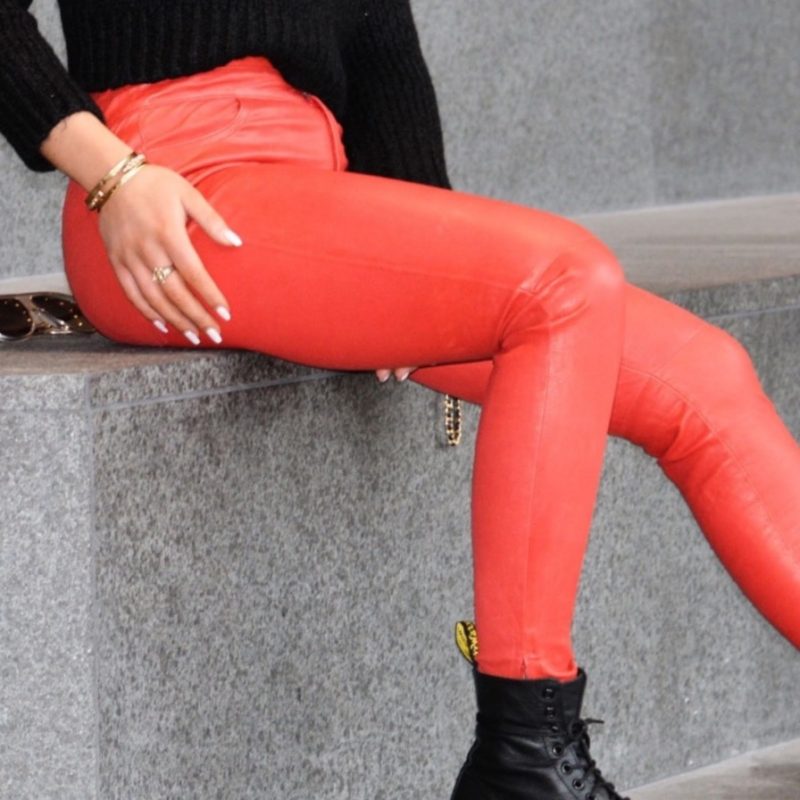 woman sitting on stairs wearing red leather pants