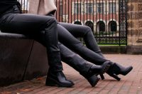 two women wearing black leather pants and black high heels