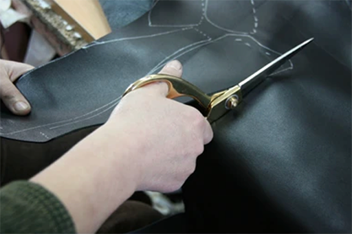 Hand cutting black leather with scissor